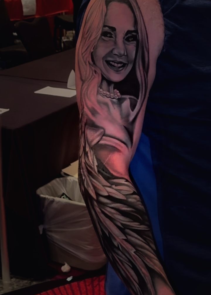 Black and grey sleeve of a woman whose figure turns into large feathered wings.