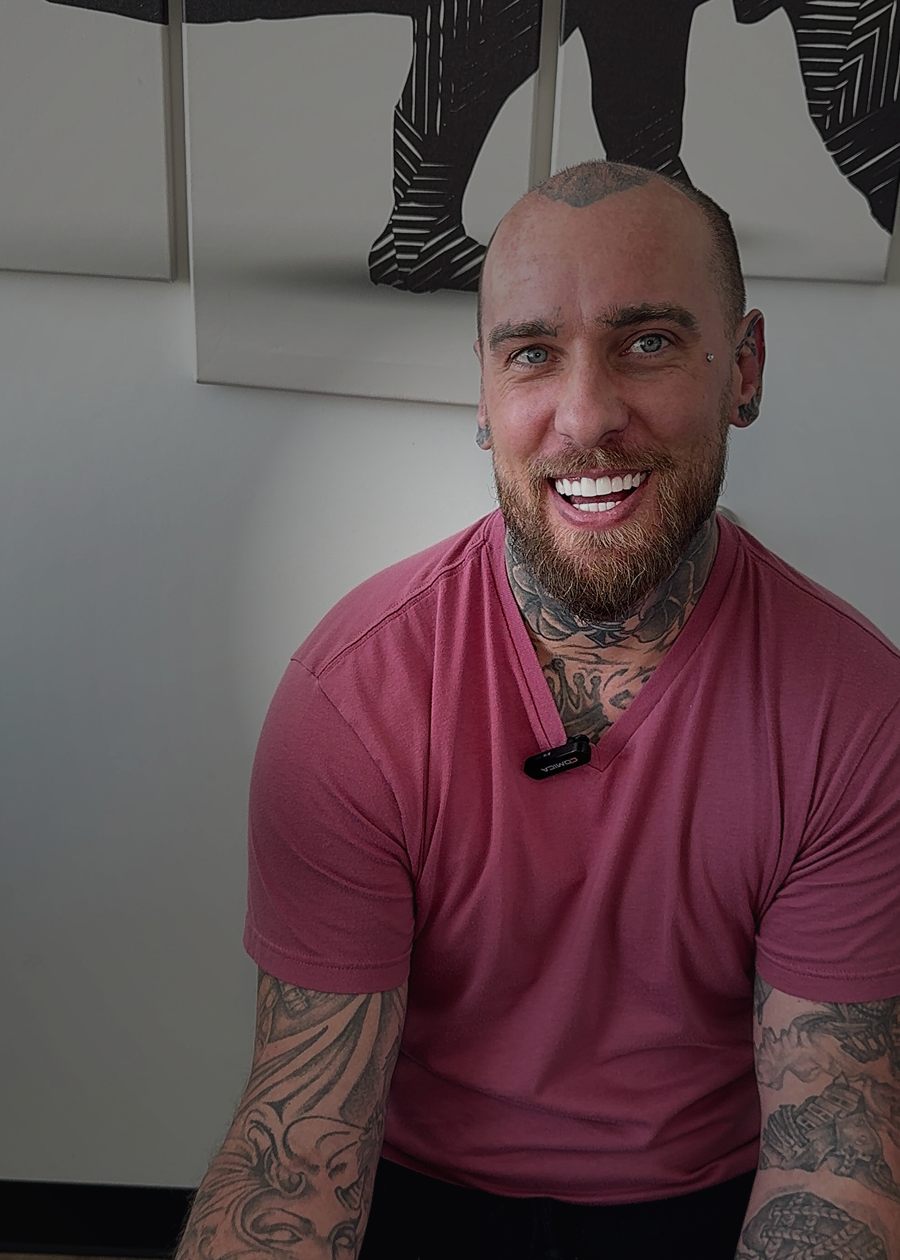 Ryan Foster, owner of Moxy Tattoo Studio, standing in the studio with both arms sleeved.