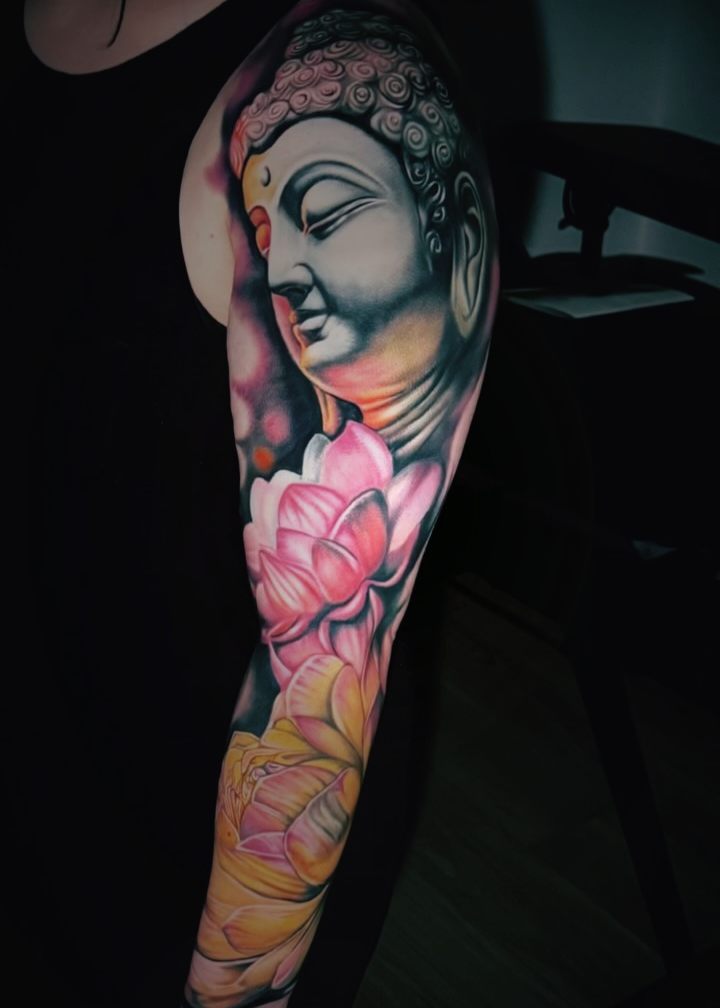 Color sleeve of a Buddha head above pink and yellow lotus flowers.