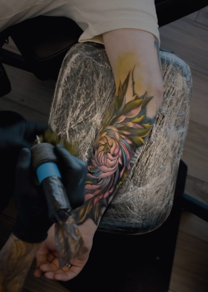 Black and grey chrysanthemum with leaves running down a forearm.