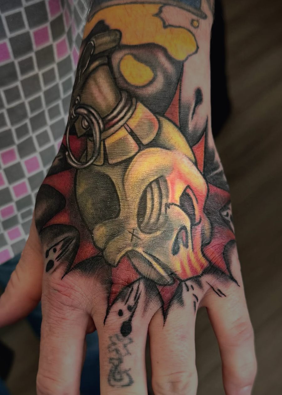 New school color grenade with a gas mask skull, tattooed on the back of a hand.