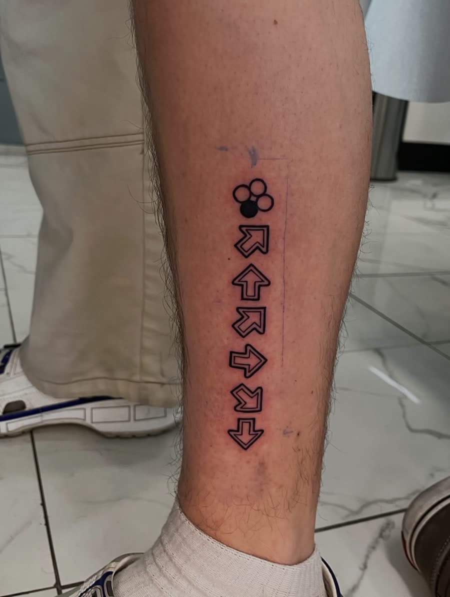 Column of small arrow and geometric symbols tattooed on a forearm.