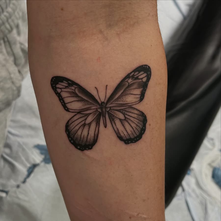 Black and grey butterfly tattooed on an upper arm.