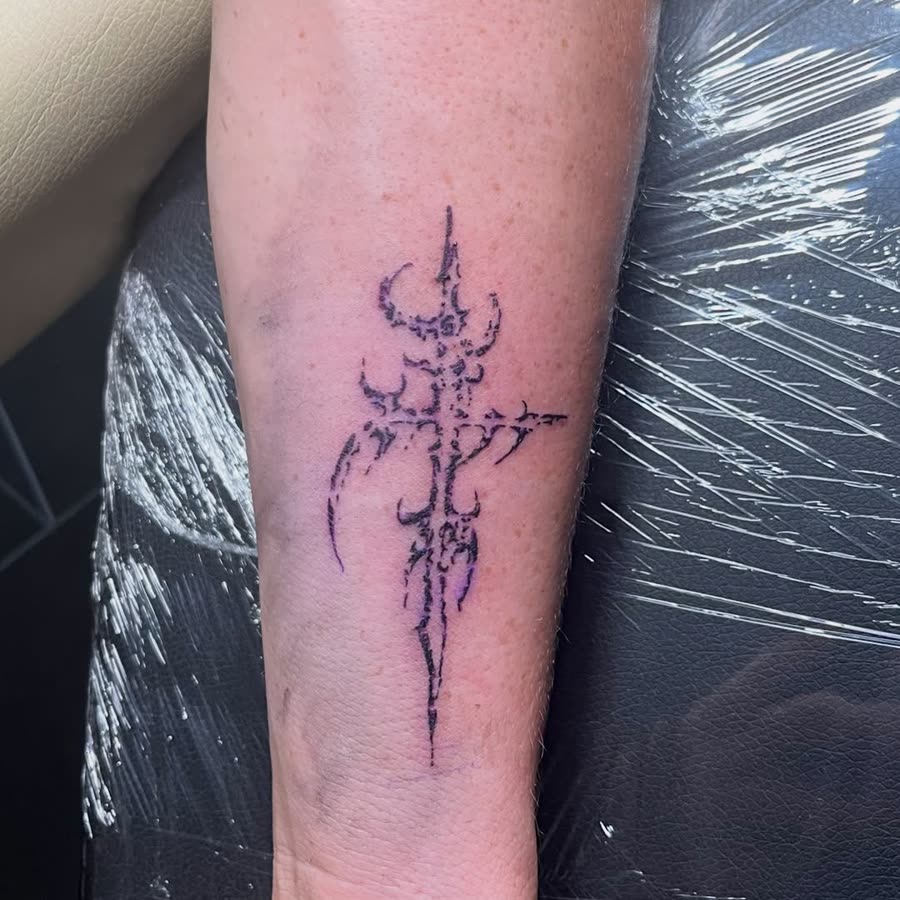 Fine line ornamental dagger tattooed on a forearm.