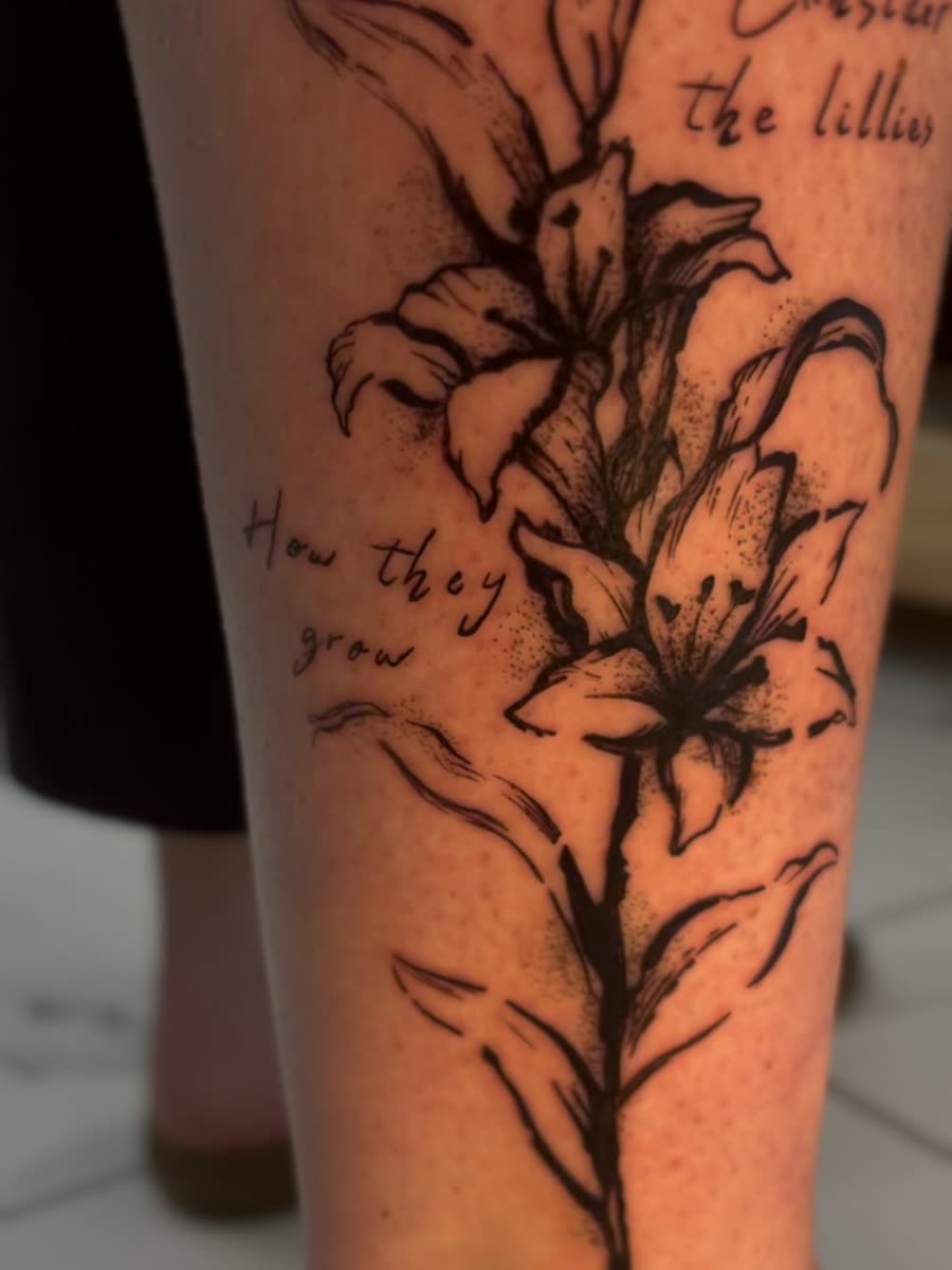 Fine line lily stems with script lettering running down a calf.