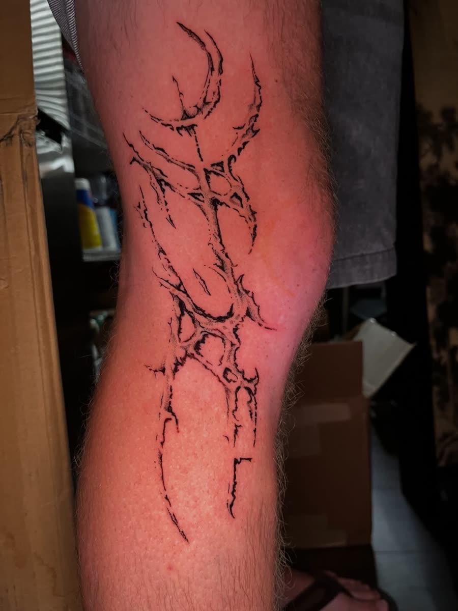 Fine line ornamental vine tattooed down a forearm.