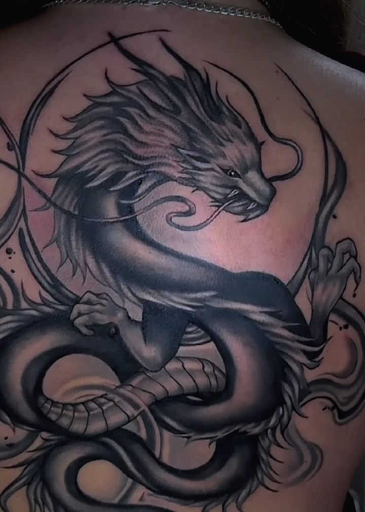 Black and grey Japanese dragon tattooed across an upper back.