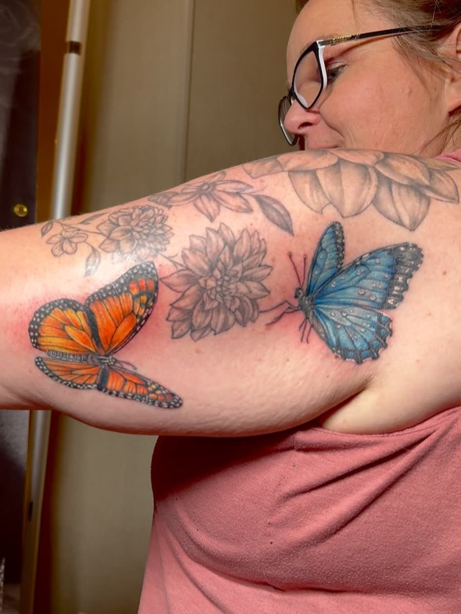 Orange and blue butterflies with fine line flowers across a shoulder.