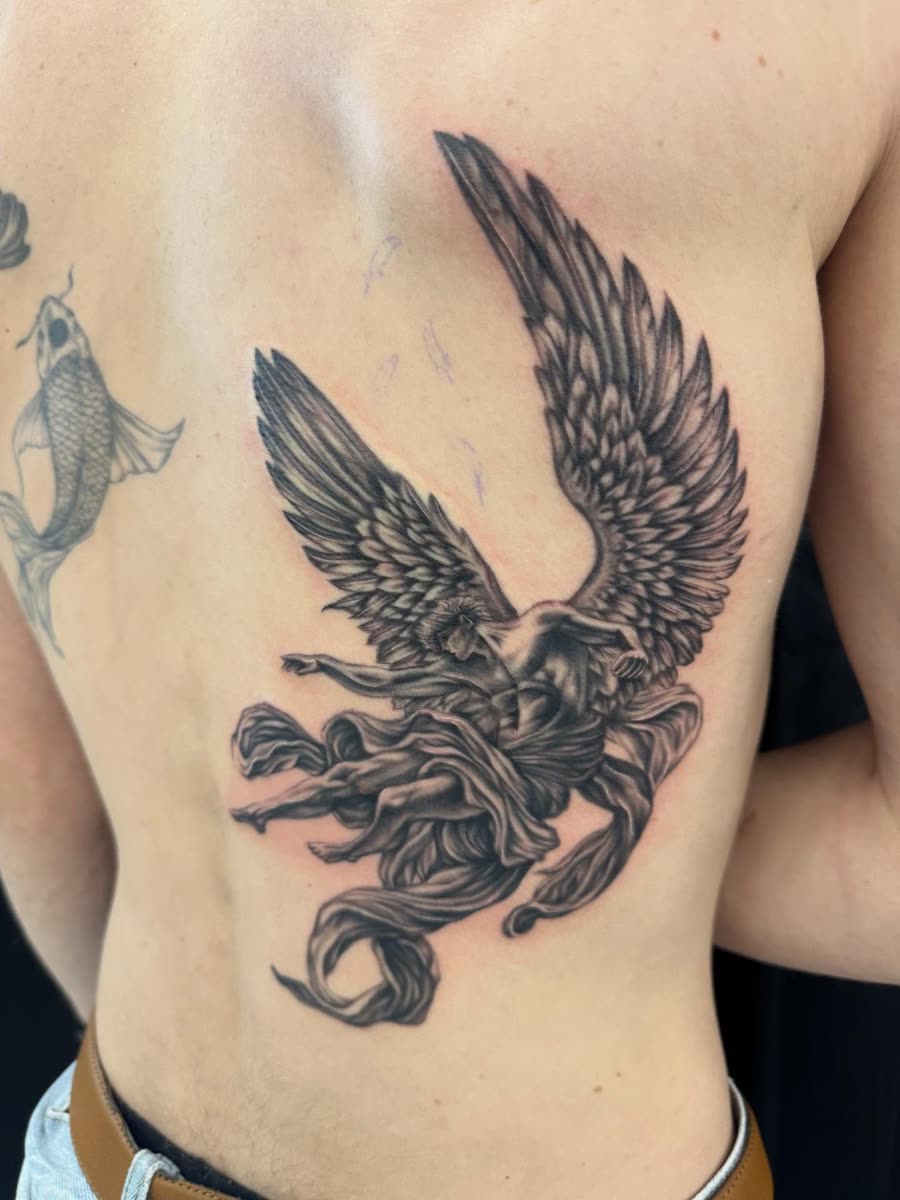 Black and grey eagle in flight tattooed across a back.