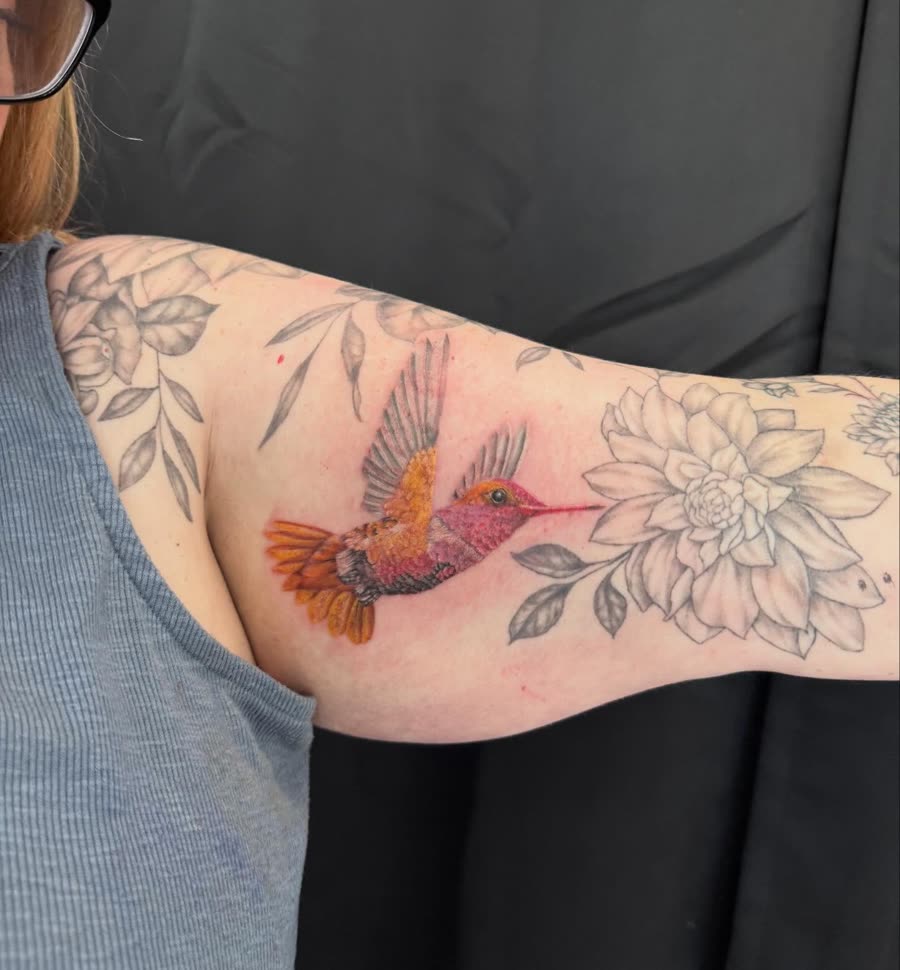Colour hummingbird with fine line flowers wrapping an arm.