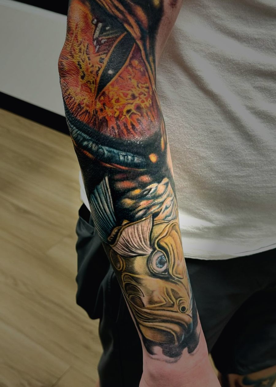 Color forearm tattoo of flames running into a golden koi head.
