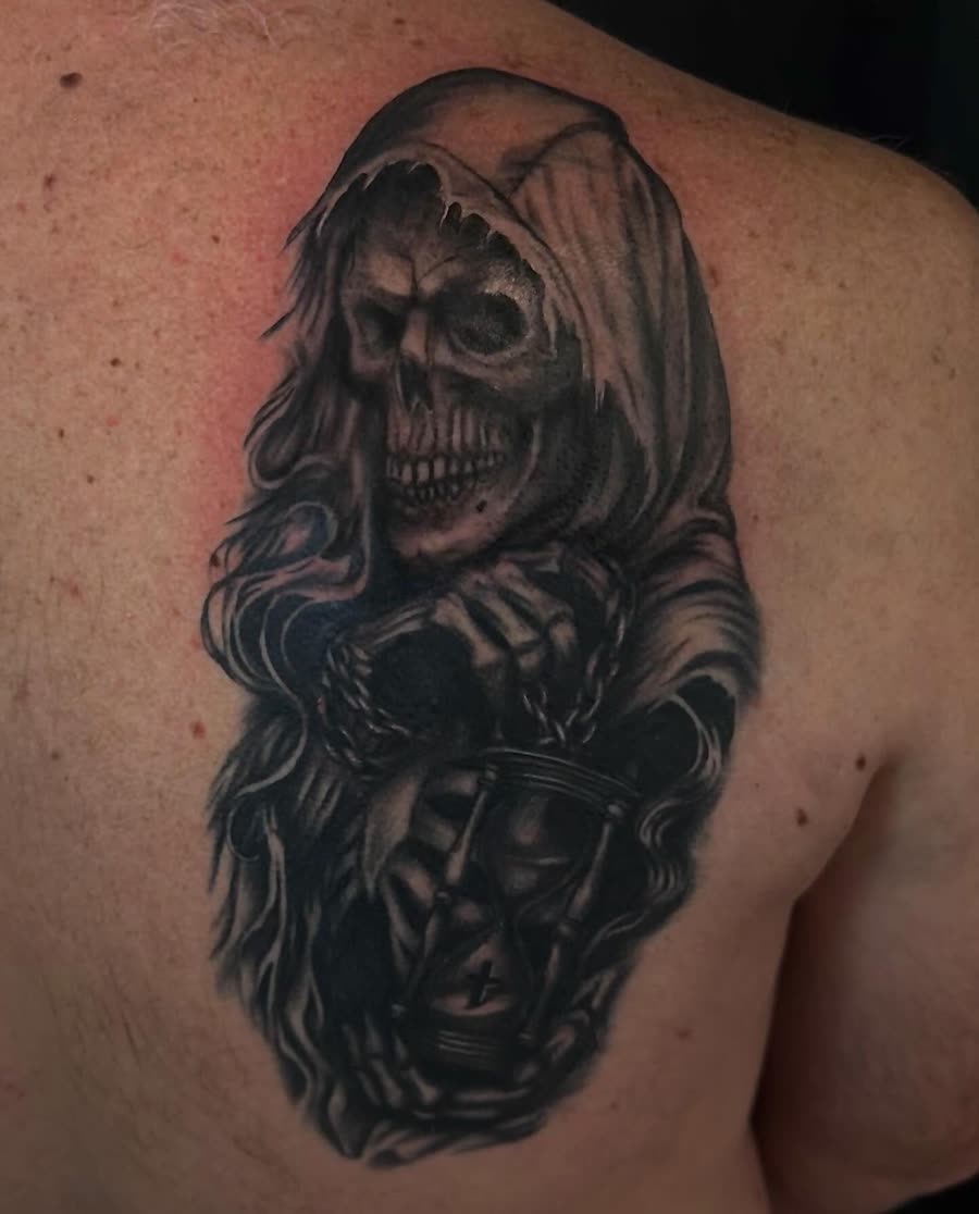 Black and grey reaper holding a lantern, tattooed across a back.