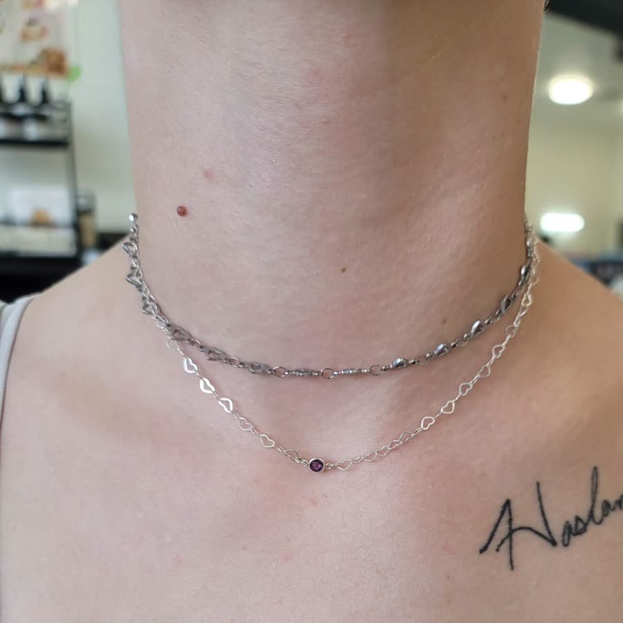 Layered fine silver permanent necklaces worn at the collarbone.