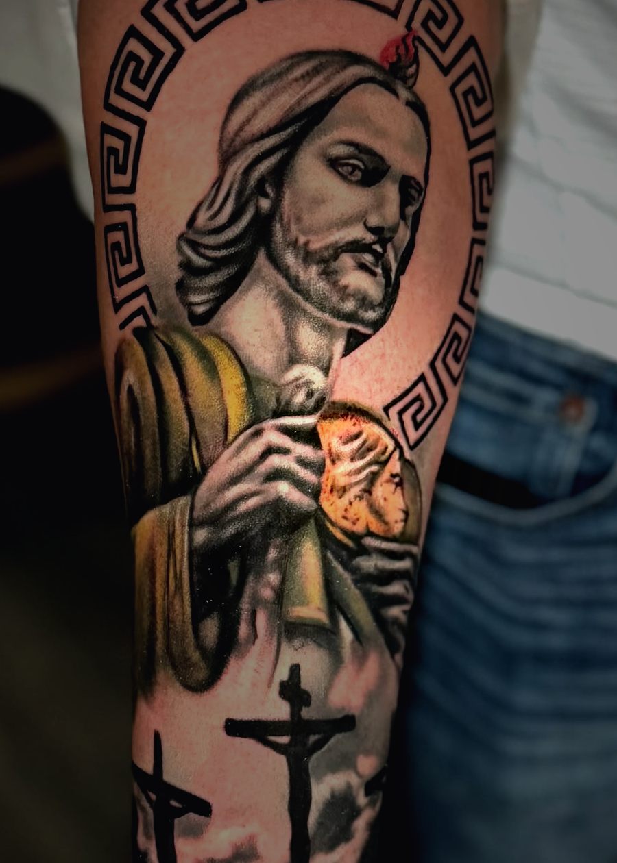 Religious forearm tattoo of Saint Jude with three crucifixes below.